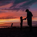 A family backlit to a gorgeous Hawaiian sunset on the beach.