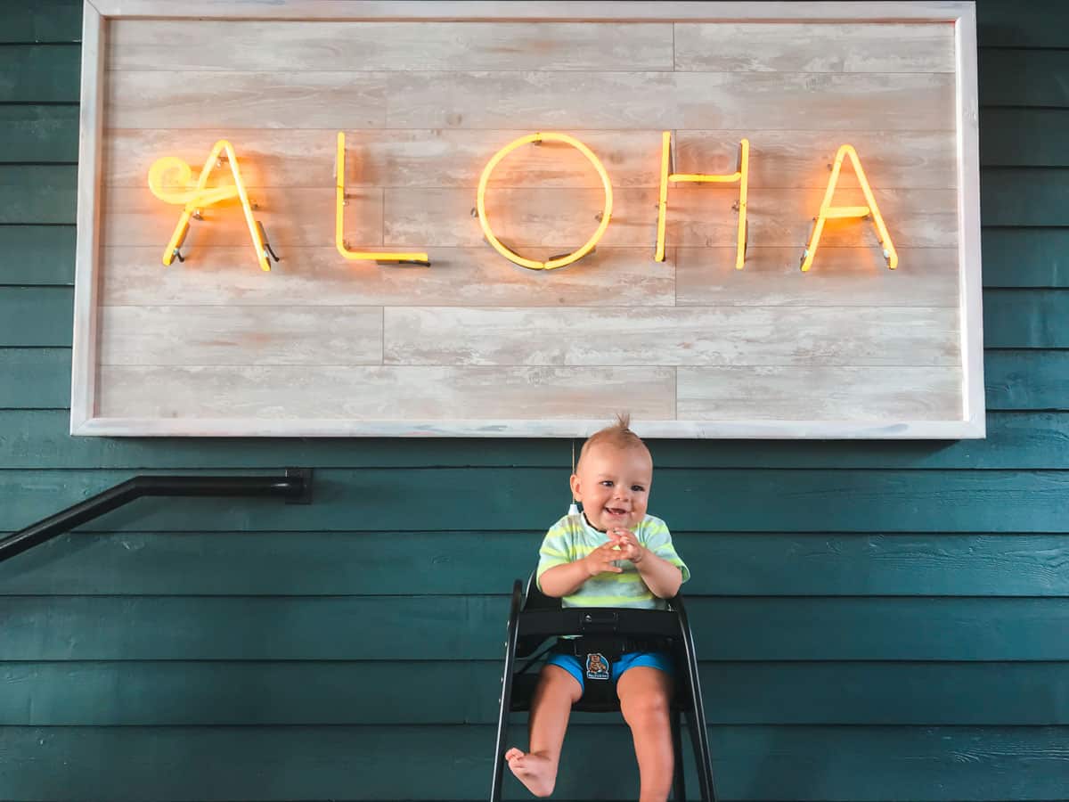 A baby in front of an aloha sign at a family-friendly restaurant on Maui. 