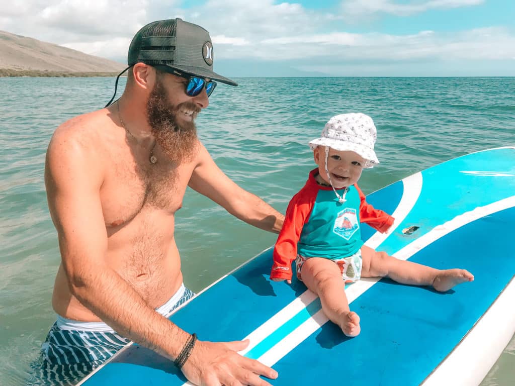 Dad with a baby on a paddle board in Maui, Hawaii.