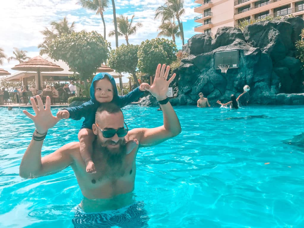 Dad with a baby on his shoulders in a resort pool in Maui, Hawaii.