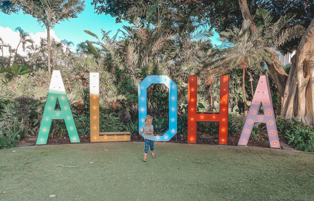 Kid running in front of an Aloha sign at a resort in Maui, Hawaii. 