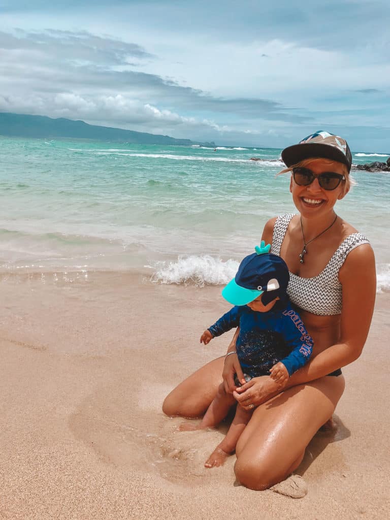 A mom holding her baby on Baldwin Beach, Maui, Hawaii.