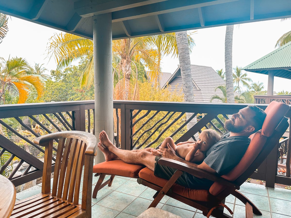 Dad relaxing with baby on a lanai at a vacation rental on the Big Island of Hawaii