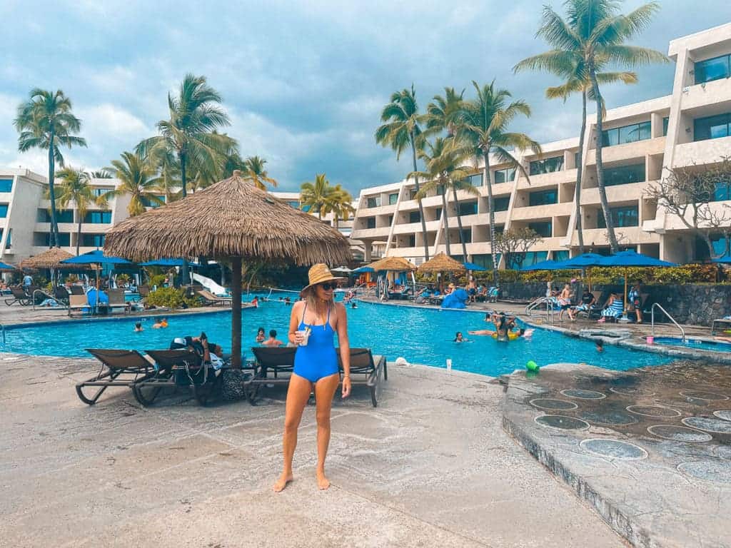 Woman Standing in front of pool with a drink in hand at Outrigger Kona Resort and Spa.