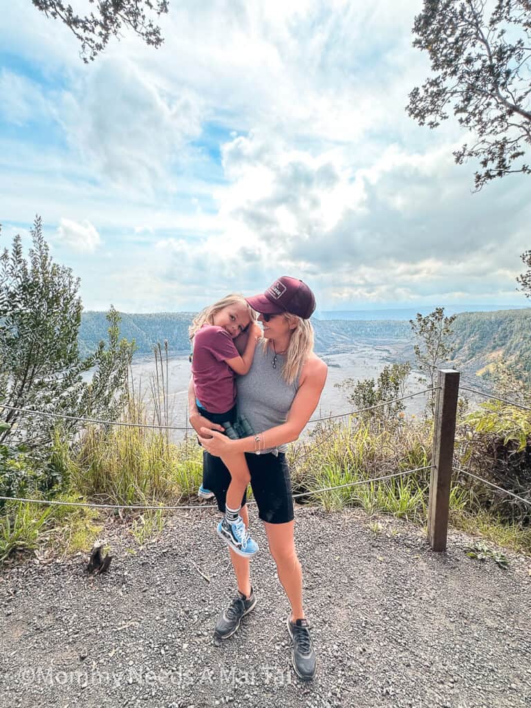 A mom holding her son at a lookout over Volcanoes National Park on the Big Island of Hawaii.