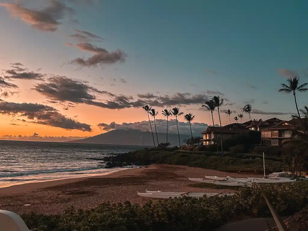 A golden sunset on a beach with the West Maui Mountains in the background in Maui, Hawaii.