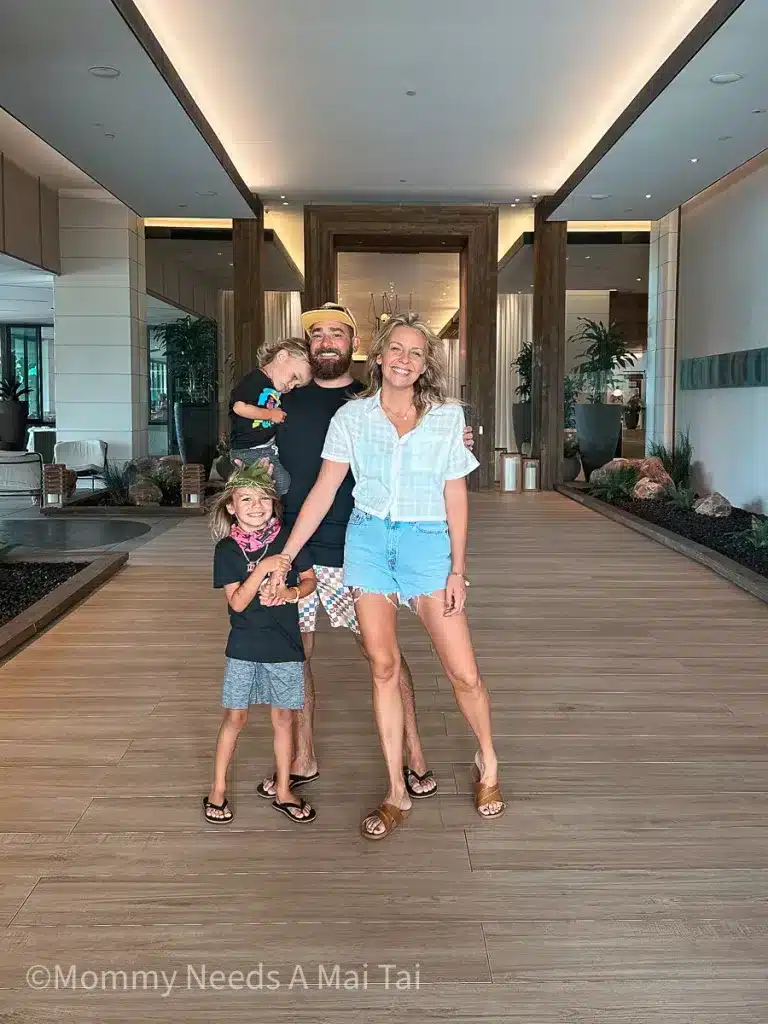 A smiling family standing in front of Turtle Bay Resort, North Shore, Oahu.