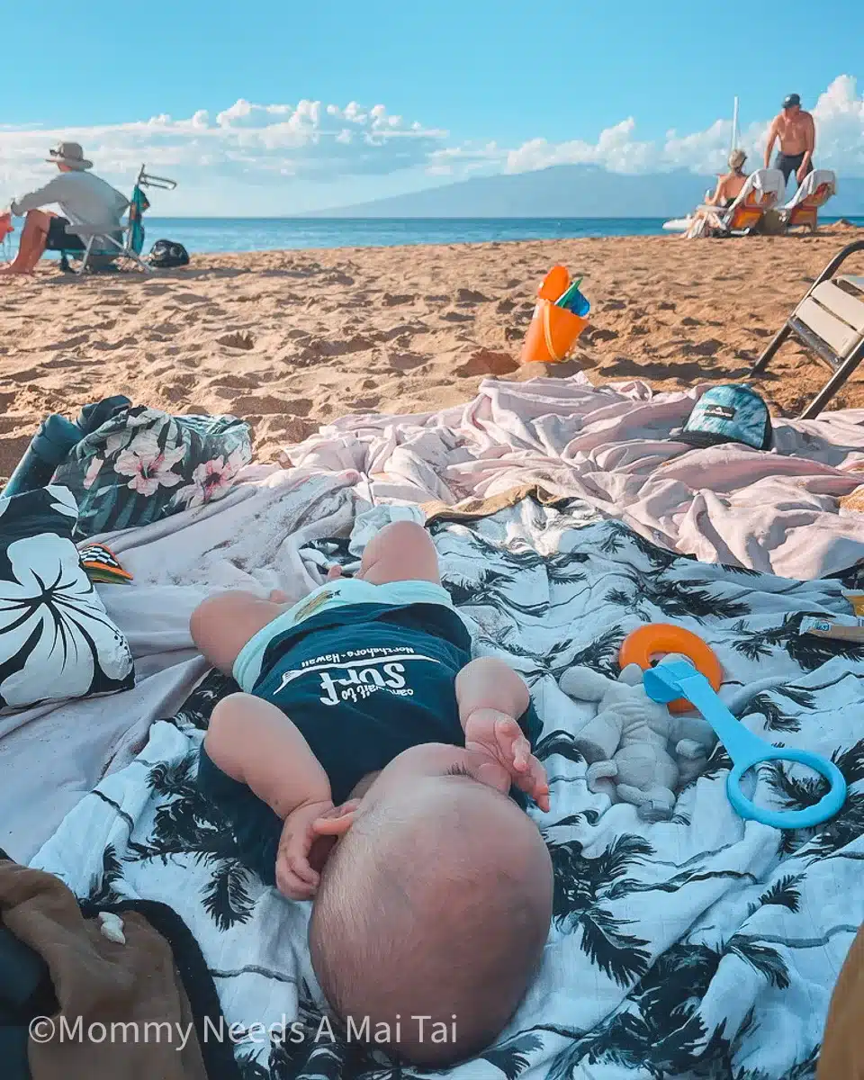 A baby lying on a blanket and sucking his thumb at Outrigger Kaanapali Beach Resort in Maui, Hawaii, steps from the sand at Kaanapali Beach.