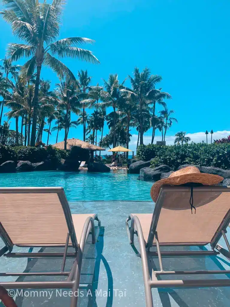 A sun hat resting on a chair in front of a resort pool at the Hyatt Regency in Maui, Hawaii. 