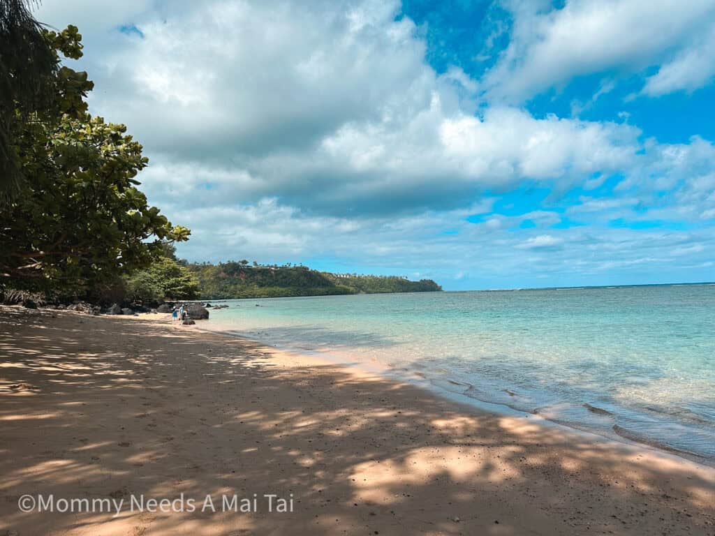 Sand and blue water with clouds in the distance at Anini Beach on the North Shore of Kauai.